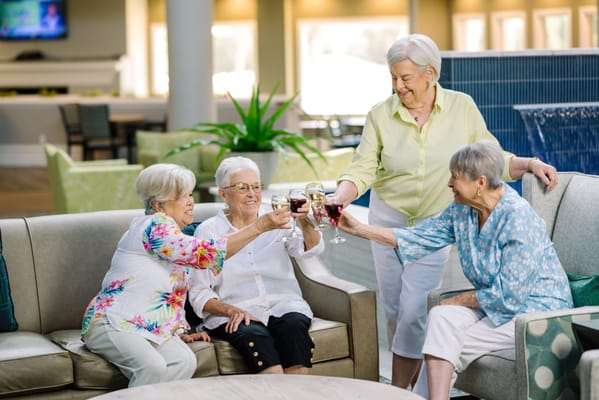 Seniors toasting with drinks in a cozy common area