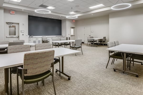 Well-lit activity room with tables and chairs