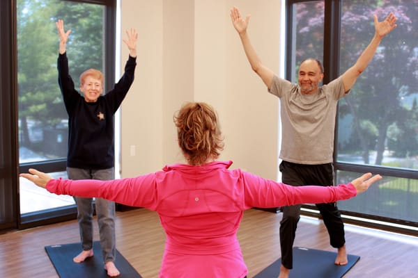 Residents participating in a yoga class in a bright activity room