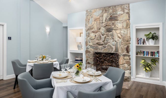 Elegant dining room setup with stone wall and bookshelves