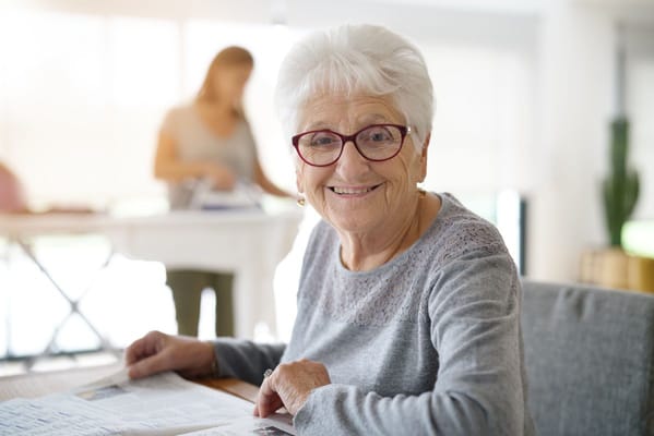 A smiling senior woman reading a newspaper indoors