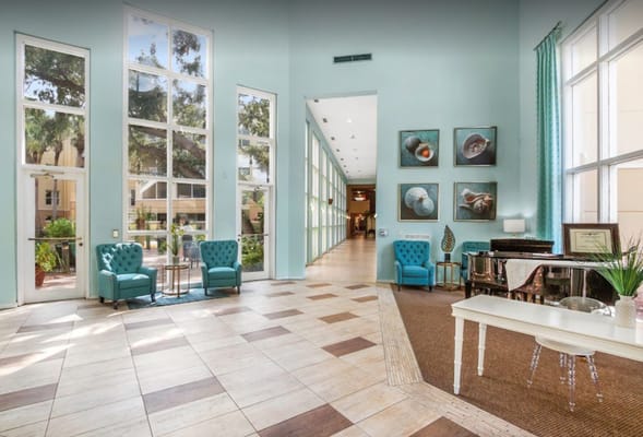 Bright common area with teal chairs and piano