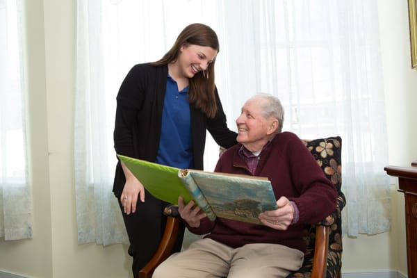 A caregiver and a resident laughing over a photo book