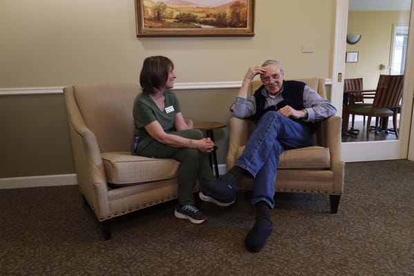 A resident and staff member sitting in a lounge area