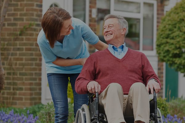 Staff member assisting a smiling resident in a wheelchair