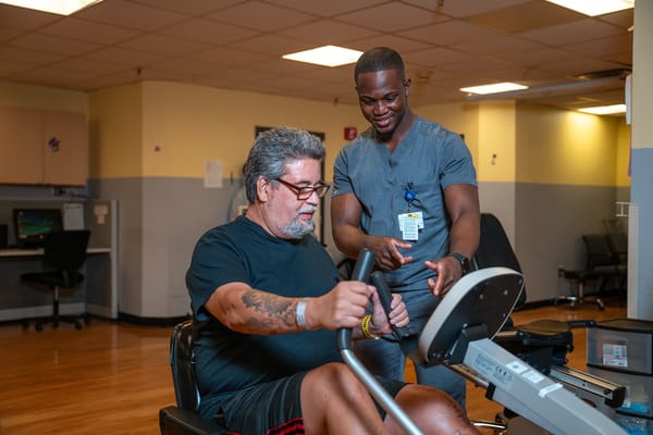 Staff assisting resident on exercise equipment