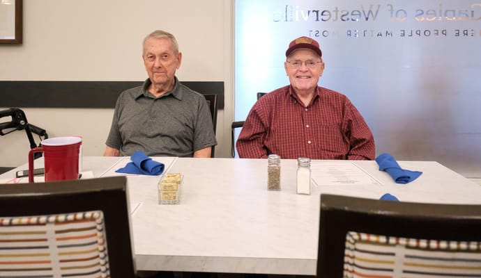 Two residents seated at a dining table in a bright dining room