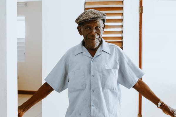 An elderly man smiling in a facility hallway
