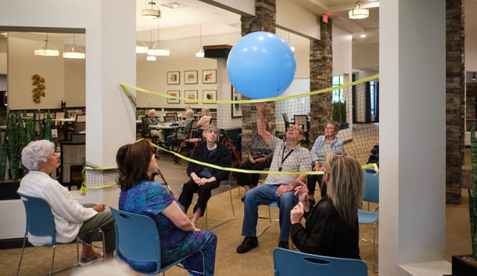 Residents participating in a balloon volleyball activity indoors