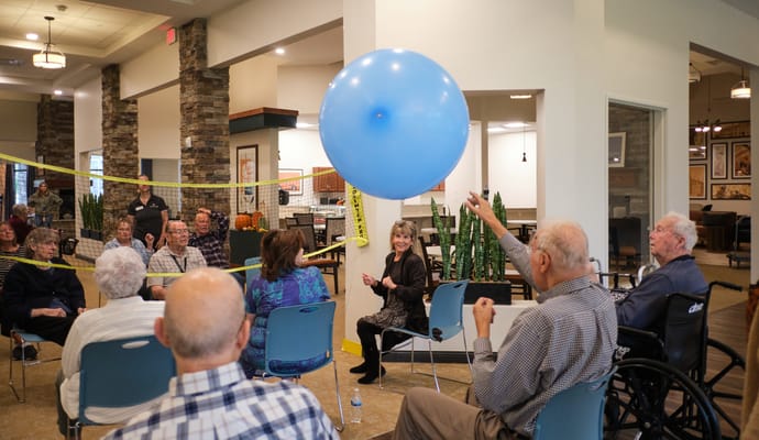 Residents engaging in a balloon volleyball activity indoors