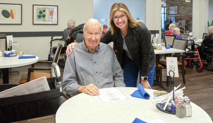 Resident enjoying a meal with staff in the dining room