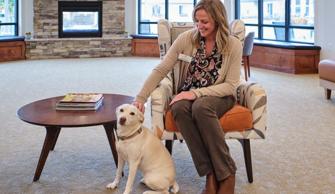 A staff member interacting with a dog in a cozy lounge area