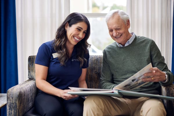 Resident and staff member looking at a photo album together