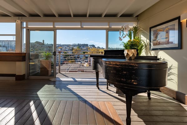 Interior view of a bright room with a piano and city view