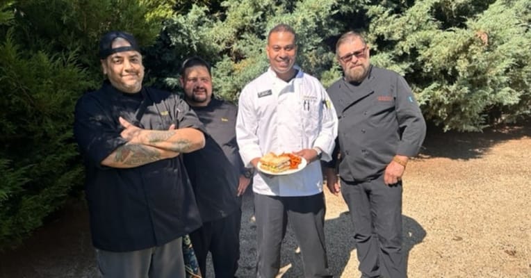 Chefs posing with a food dish in an outdoor setting
