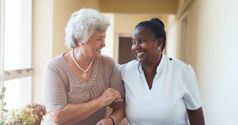 A caregiver and resident smiling together in a hallway