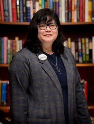 Staff member posing in front of a bookshelf