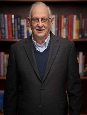 An elderly man standing in a library setting