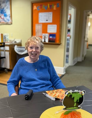 A resident smiling in a common area with activities displayed