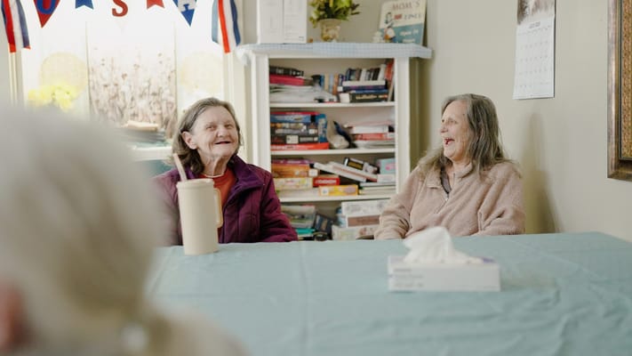 Two women laughing together in a common area.