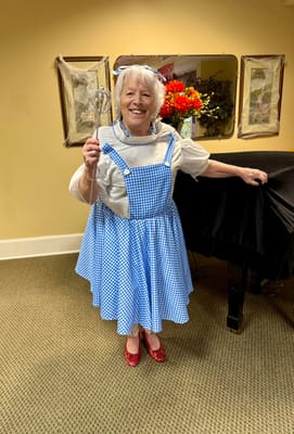 A resident dressed in costume holding a wand in a common area