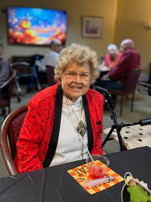 A cheerful elderly woman enjoying a drink at a social gathering