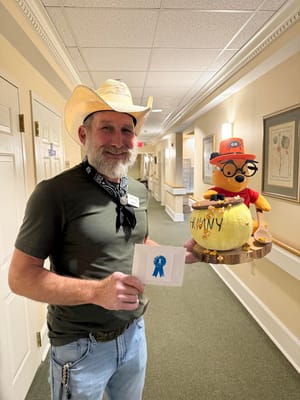 Staff member holding a prize with a decorated toy in the hallway