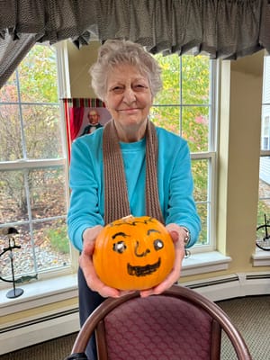 Resident holding a decorated pumpkin in a common area