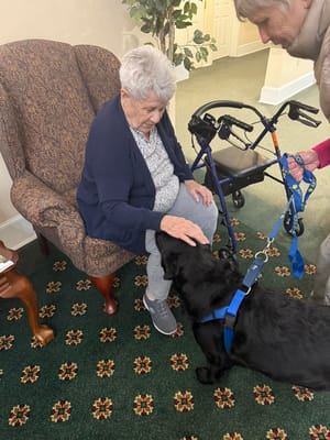 Resident interacting with a therapy dog in a cozy setting