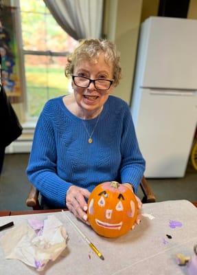 Resident decorating a pumpkin in an activity room