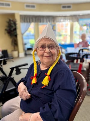 Cheerful elderly resident in a common area wearing a playful hat