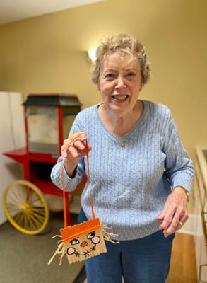 Resident holding a handmade craft in the activity room