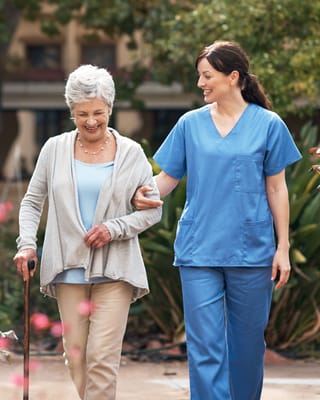 A resident and staff member walking in a garden
