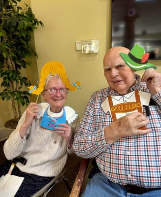 Two residents posing with festive props in a common area