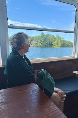A senior man looking out of a boat window at a lake