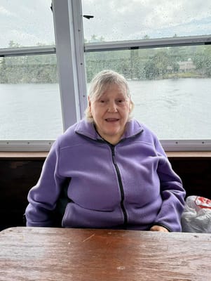 A senior woman sitting on a boat with a lake view