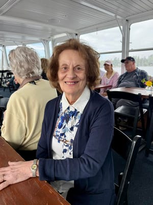 Elderly woman smiling at a table with others in a social setting