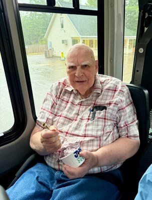 A resident enjoying ice cream on a facility bus