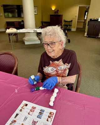 Resident engaging in a craft activity with gloves on