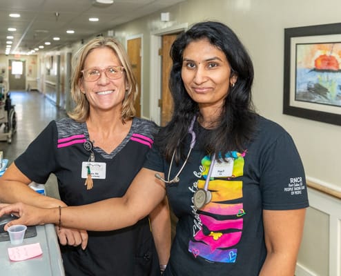 Two staff members smiling in a facility hallway