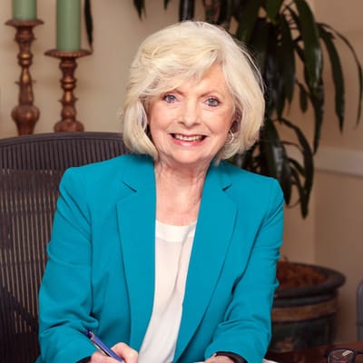 A smiling resident in a bright blue jacket at a desk