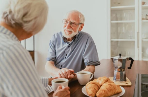 Two seniors enjoying coffee and pastries at a table