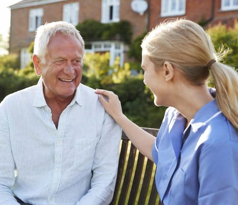 Resident chatting with caregiver in a garden setting