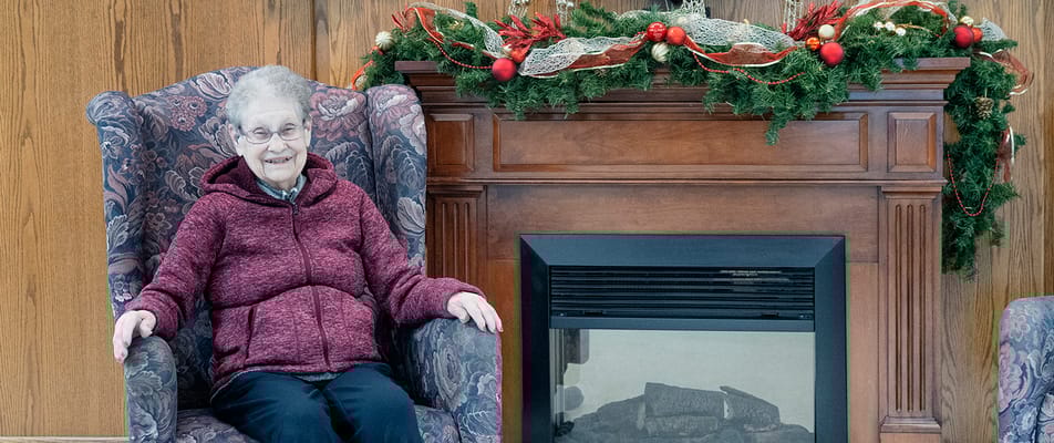 Resident sitting by a festive fireplace