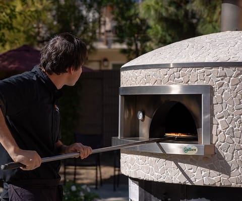 Staff member using an outdoor pizza oven
