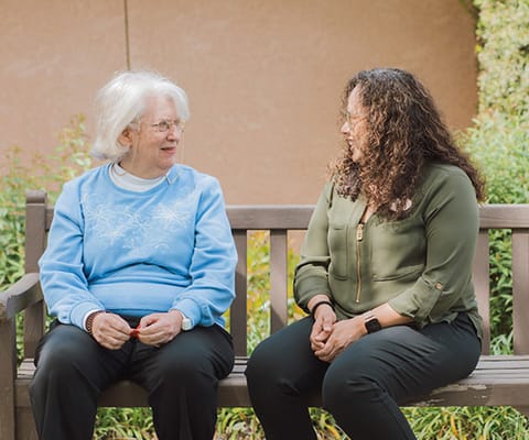 A resident conversing with a staff member on a bench