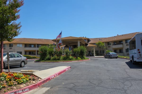 A sunny view of the entrance area with landscaping and American flags