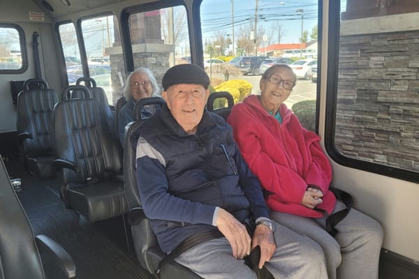 Three residents seated in a facility vehicle, smiling