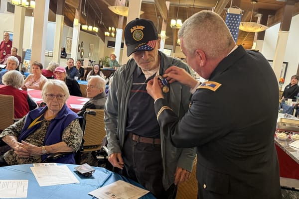 Veteran receiving a medal with residents and staff present