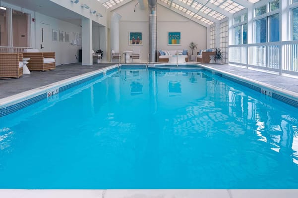 Indoor swimming pool with lounge seating and natural light